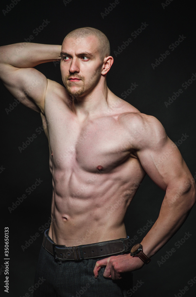 Sporty sexy man stands Topless on a dark background. Sports, beauty