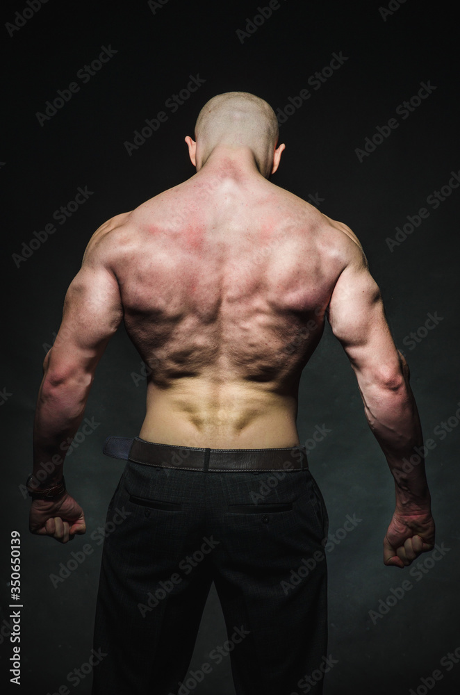Fototapeta premium Sporty sexy man stands Topless on a dark background. Sports, beauty