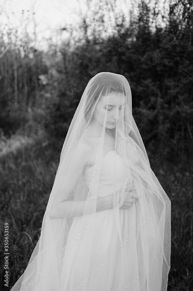 Fine art portrait of a bride in a long veil in nature