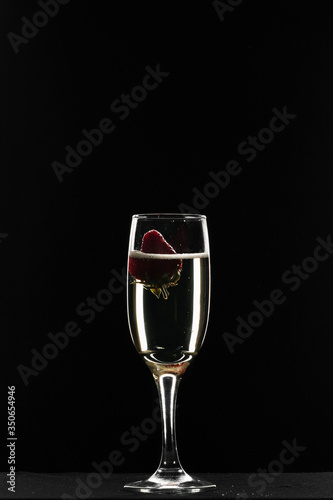 Strawberry floats in a glass of champagne on a black background