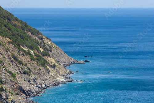 Coastline with cliff mountain and seashore view. Pitched rock face on the sea. Elba island in Italy. Aerial view. Green vegetation.