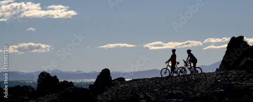 Cyclists silhouette against blue sky, New Zealand.