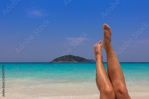 Beautiful woman with legs raised up high in the air. Similan Islands, white sand, blue water.