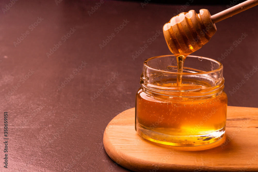Honey dripping from honey dipper in jar. Honey dripping from honey dipper in jar.