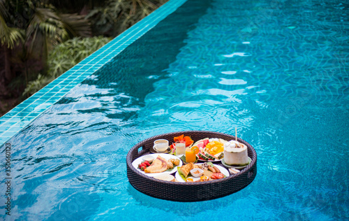 Breakfast in swimming pool, floating breakfast in tropical resort. Fruit plate by resort pool. © Anna