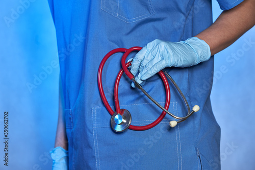 Hand of a doctor in medical glove with stethoscope, closeup, Coronavirus epidemic COVID-19