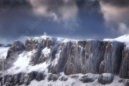 Fototapeta Naklejka Na Ścianę i Meble -  Winter landscape with a cliff and a white gazebo on the edge on a cloudy day