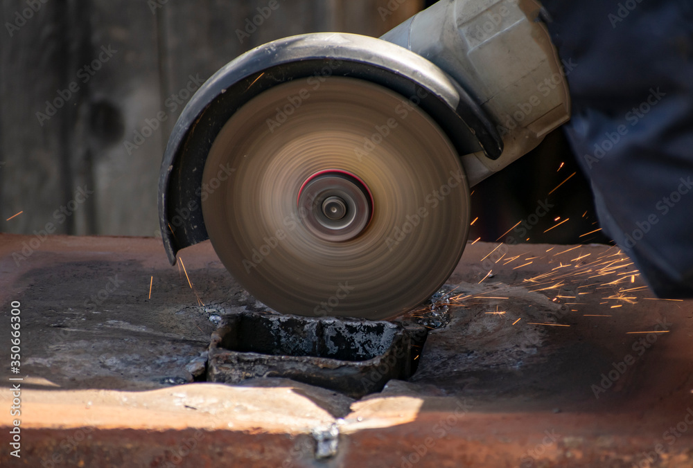 A man processes rusty metal structures with a manual grinder. A man processes rusty metal structures with a manual grinder.