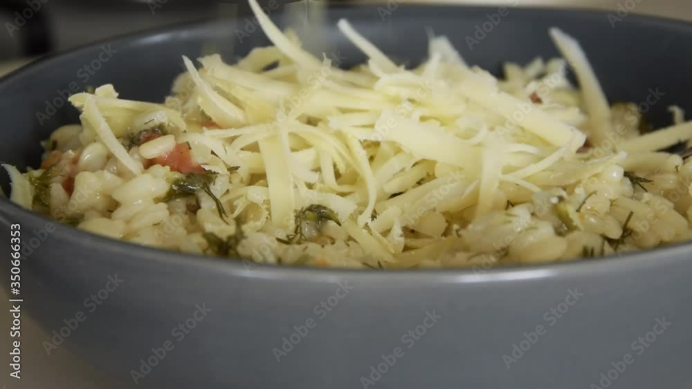 Close up view of grating cheese over hot risotto, slow motion
Close up view of grating cheese over hot risotto, slow motion