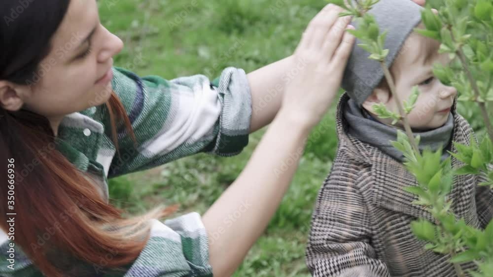 Boy child in a coat plays with leaves