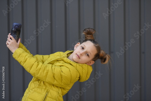 Beautiful girl in a yellow jacket. The child holds a thermos in his hands with tea. Child on a walk