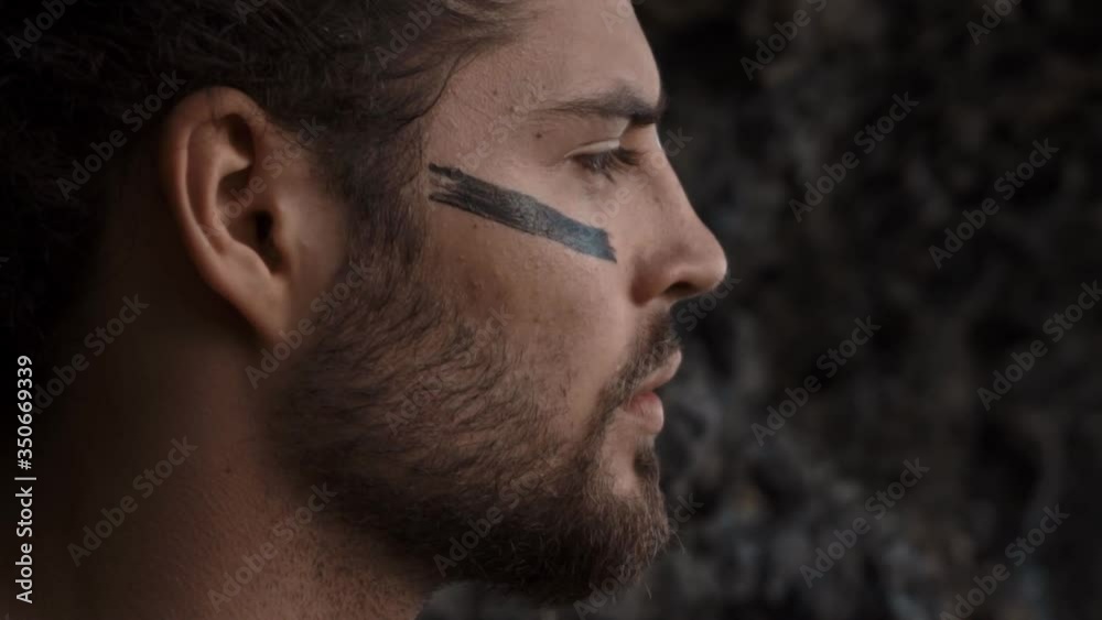 handsome and courageous European man with drawings on his face looks into the distance handsome and courageous European man with drawings on his face looks into the distance