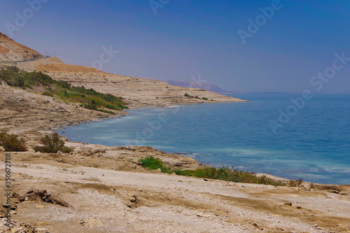 The coast of the dead sea against the backdrop of the mountains and the blue sky. 