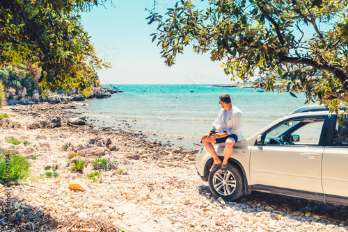 man with coffee cup standing near car at sea summer beach