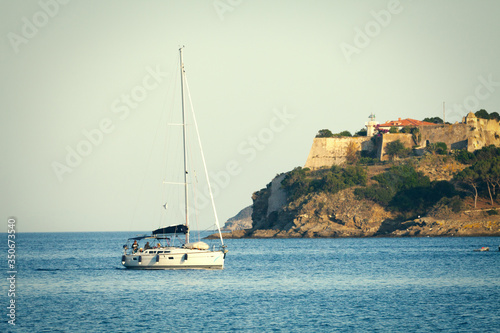 Sea with sailboat. Elba Island in Italy. Lighthouse on the rock of Porto Azzurro.