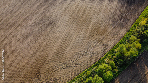 Black agricultural field and green trees aerial landscape view from drone, beautiful natural texture background from above
