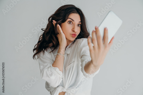 pretty young girl in white shirt make a duck face, and take a self portrait with her smart phone. Life style concept. stupid face