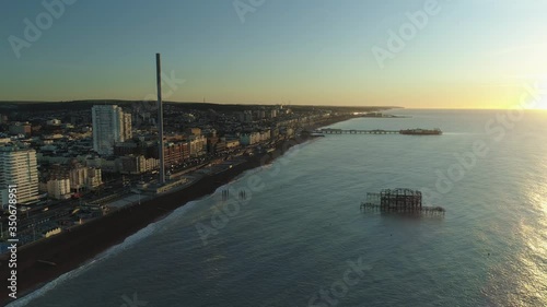 Brighton West Pier, British Airways i360 viewing tower and Brighton Palace Pier at sunrise with calm sea panning to see town photo