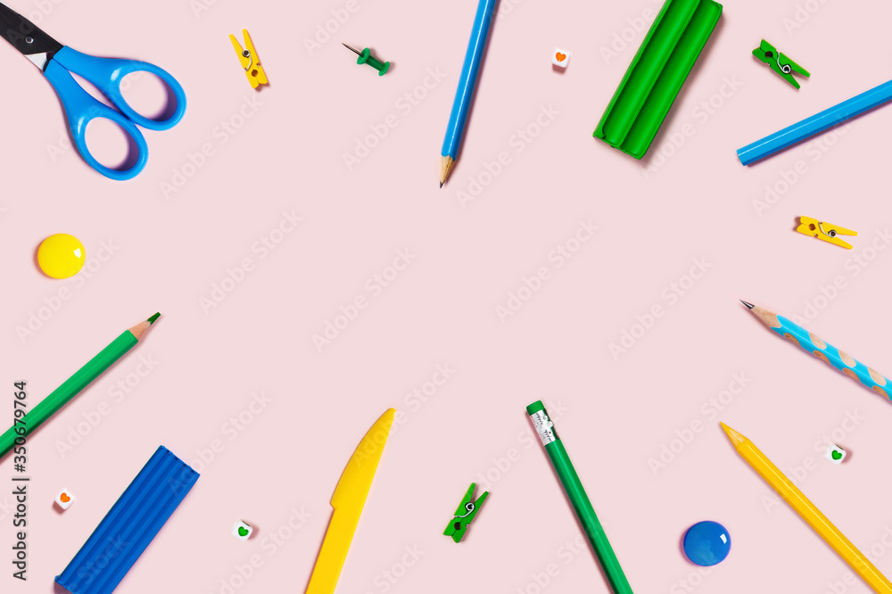Pink background with writing materials. Back to school flat lay with colored pencils, scissors, plasticine, and paper clips. Pink background with writing materials. Back to school flat lay with colored pencils, scissors, plasticine, and paper clips.