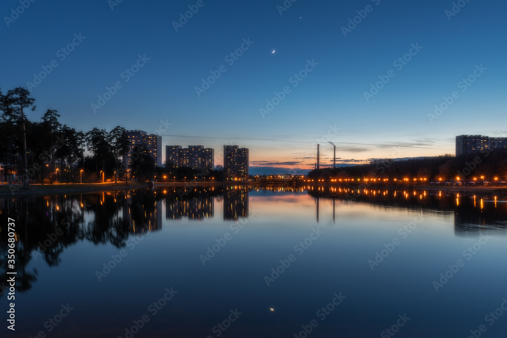 The conjunction of the Moon and Venus in the evening sunset sky over a lake in the very center of Zelenograd
