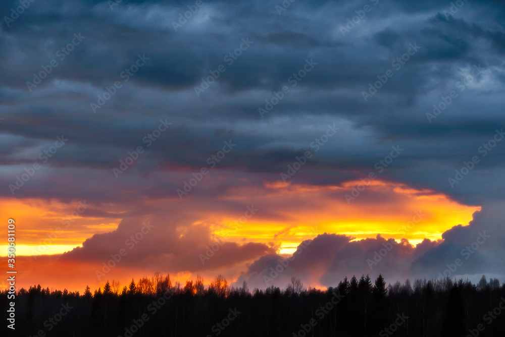Fototapeta premium Sunset light through thunderclouds on the river bank.