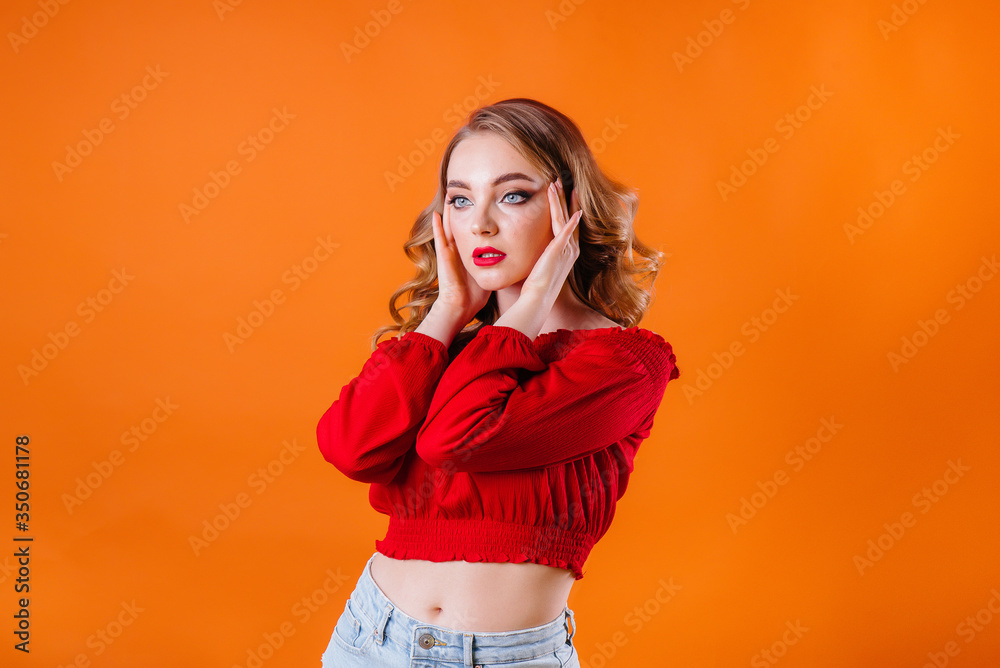 A young beautiful girl shows emotions and smiles in the Studio on an orange background. Girls for advertising A young beautiful girl shows emotions and smiles in the Studio on an orange background. Girls for advertising