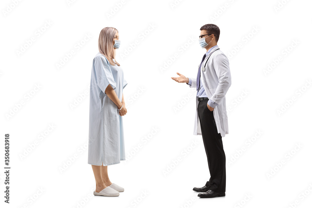 Female patient in a hospital gown and a male doctor talking and wearing protective masks Female patient in a hospital gown and a male doctor talking and wearing protective masks