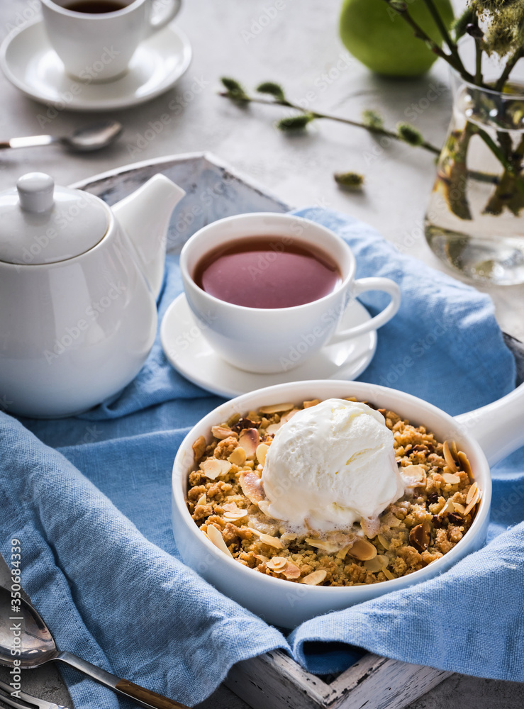 Fototapeta premium Apple crumble with a scoop of vanilla ice cream and tea on a wooden tray. Breakfast concept