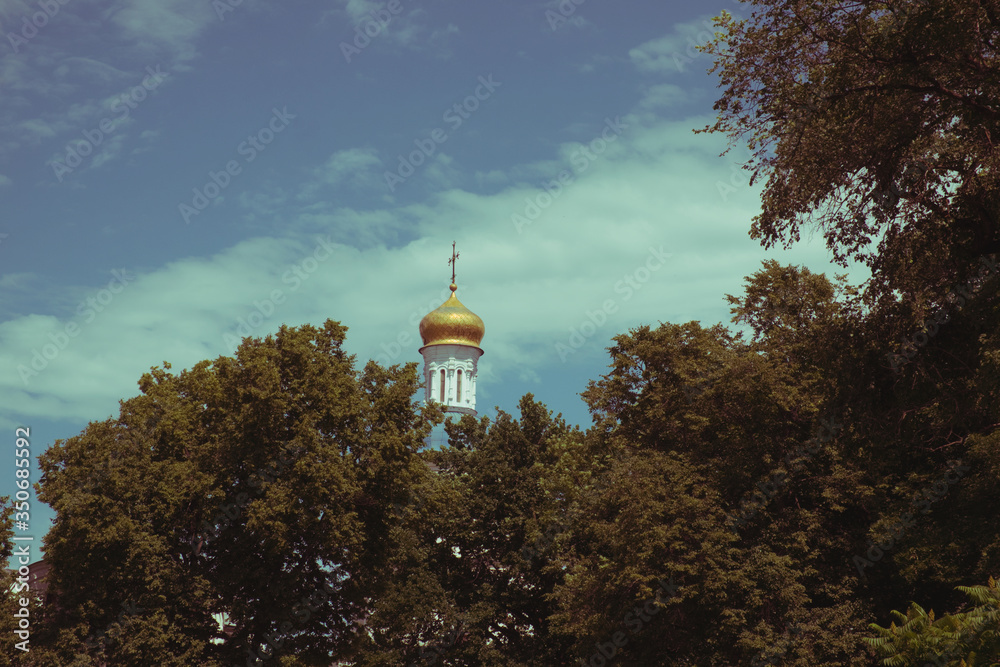 The dome of the Orthodox church over the trees. Golden dome against the blue sky. Autumn landscape.
