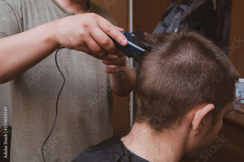 A man holds a hair clipper in his hand. The process of cutting hair close-up. View from the back of the head