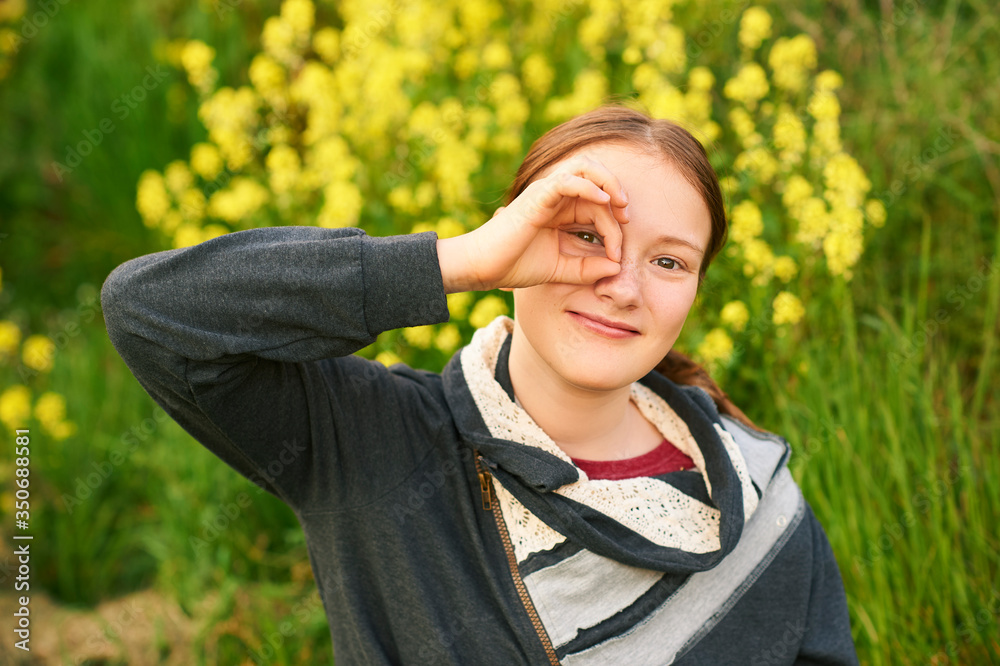 Naklejka premium Outdoor portrait of young teen girl looking through fingers