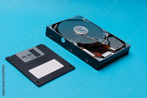 Close up of the inside of a Hard Drive and floppy disk on blue background. data storage concept. Topical data storage unit repairs. information backup and security concept. file recovery services.