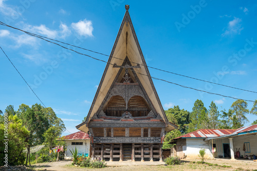 Traditional Batak house, in Indonesian called Rumah Bolon or Jabu, are noted for their distinctive roofs which curve upwards at each end, as a boats hull does and their carving decor photo
