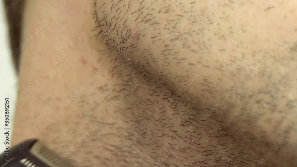young man shaving with an electric razor. The guy shaves his beard with a razor close-up macro.
young man shaving with an electric razor. The guy shaves his beard with a razor close-up macro.