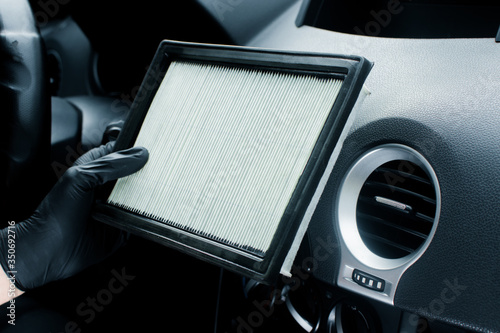 Technician holding pollen filter of car air conditioner. Maintenance and repair concept of the air conditioning and heating piping system. Workshop topic and car repairs. Automobile dashboard.