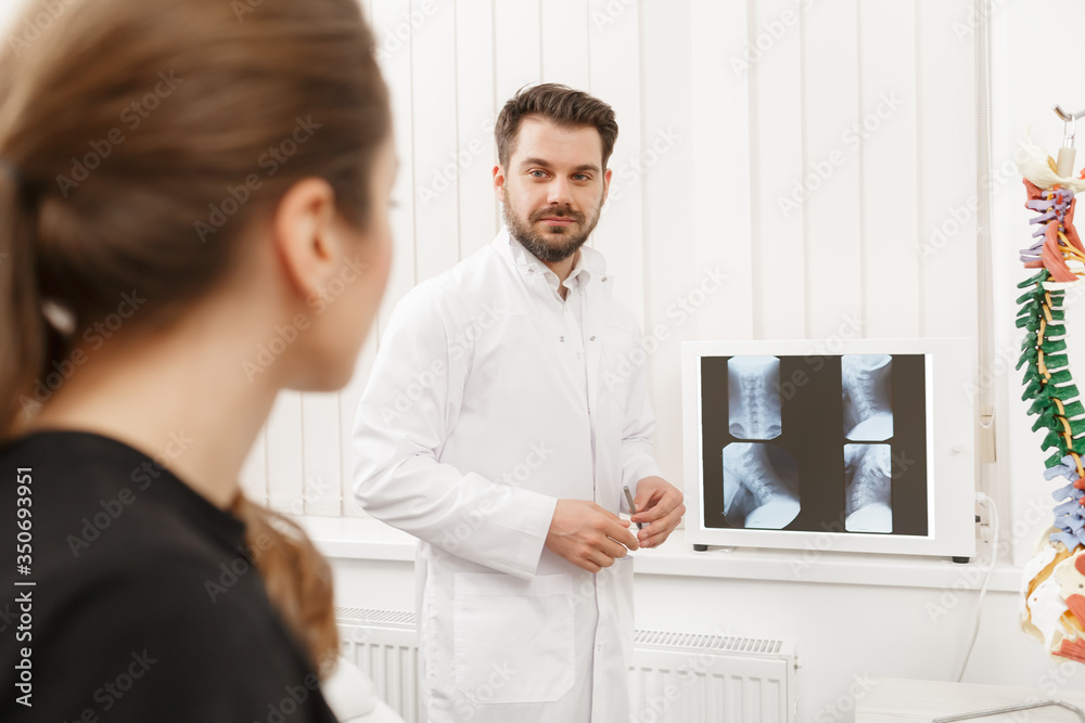 Doctor showing results of X-ray examination to his patient and explains the cause of her pain in medical office. Patient visiting physiotherapist in clinic. Surgery, healthcare and medicine concept.