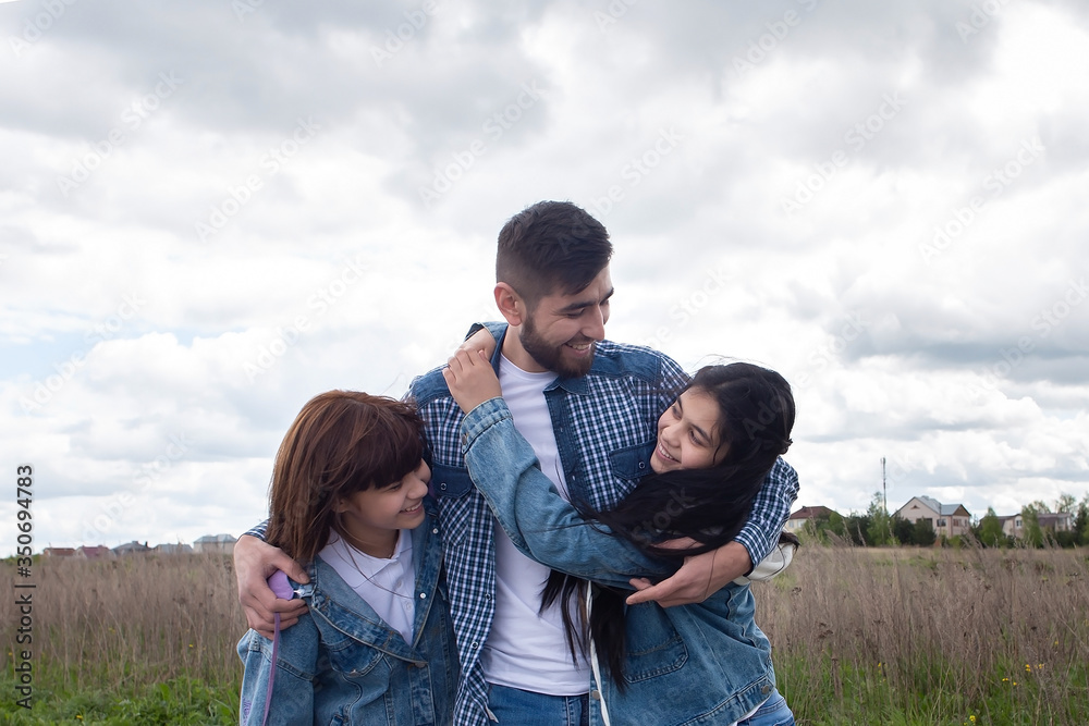 Young and happy father hugs his children, photo for Father's Day