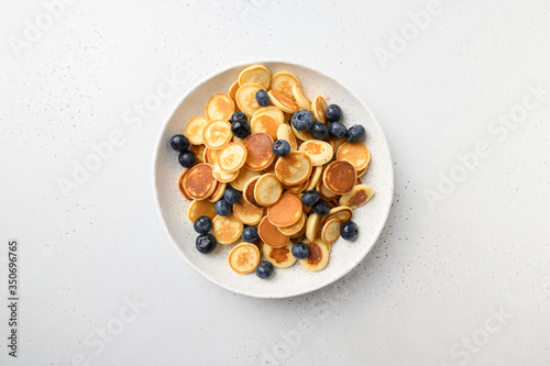 Tiny pancakes with blueberry on white background. View from above.