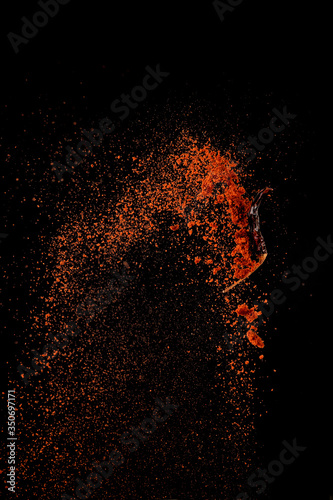 Red paprika spices powder explosion  flying chili pepper isolated on black background. Splash of spice background.