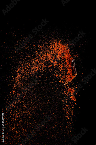 Fototapeta Naklejka Na Ścianę i Meble -  Red paprika spices powder explosion, flying chili pepper isolated on black background. Splash of spice background.