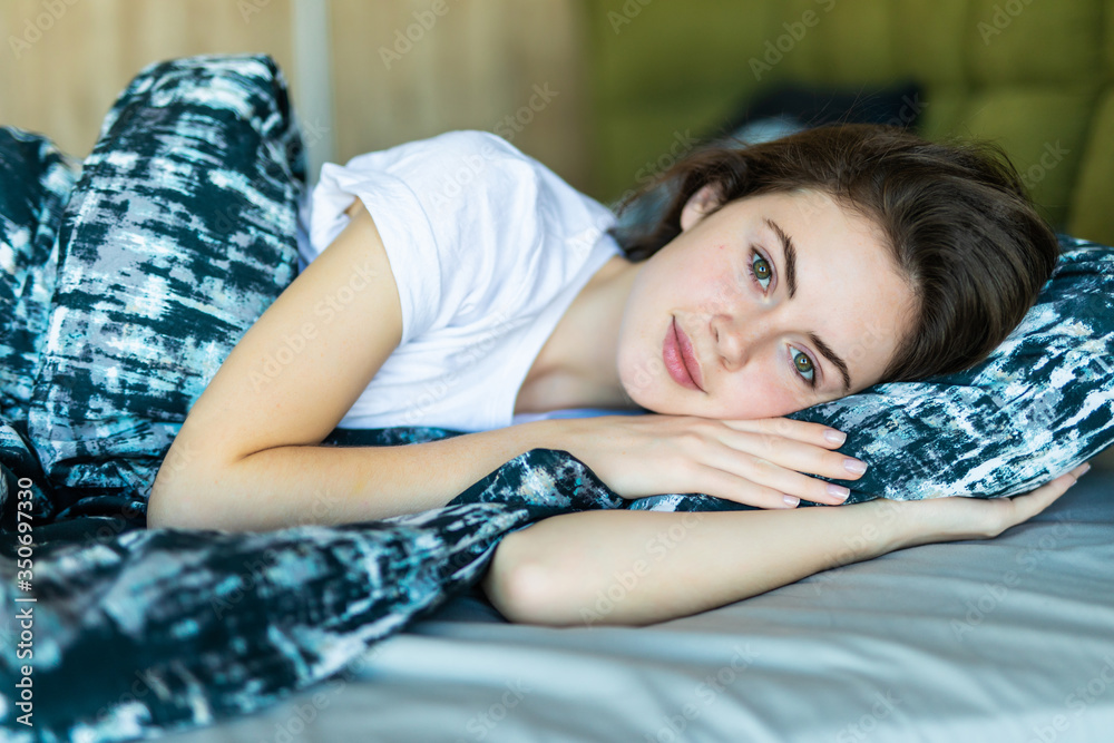 Smiling casual brunette woman lying in her bed in bedroom Smiling casual brunette woman lying in her bed in bedroom