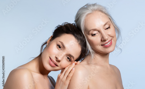 Beautiful smiling brunette adult daughter and grey-haired senior mother portrait. 