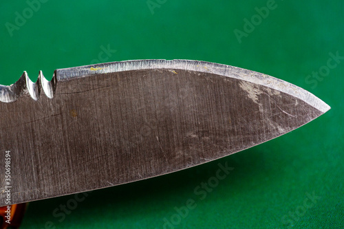 Cutting edge of blunt knife with damaged blade on green background close up