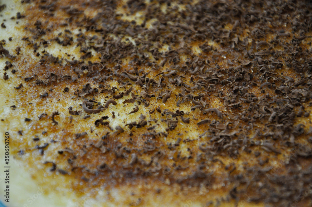 Raw dough layer covered with grated chocolate, white sugar and ground cinnamon before make a roll for Danish buns. Close up. Raw dough layer covered with grated chocolate, white sugar and ground cinnamon before make a roll for Danish buns. Close up.