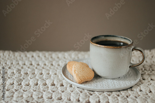 Cozy breakfast, a cup of coffee and cookies on biege knitted blanket with copy space