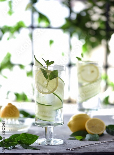 Lime, cucumber, parsley cocktail, lemonade, detox water with ice cubes in a glasses on a white plate. Detox cucumber and mint diet drink, healthy summer cooler. 