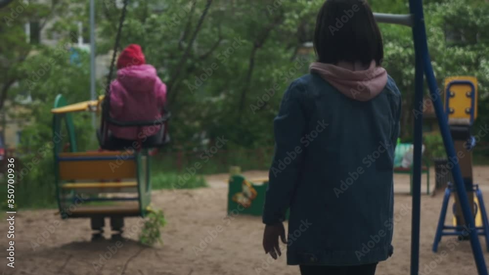Young mother pushes daughter on a swing. Little girl on the playground. Young mother pushes daughter on a swing. Little girl on the playground.