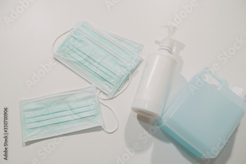 Products to stay safe in covid19 quarantine. Sanitiser gel for hands and medical face masks on blue abstract background. Protection during coronavirus pandemic.