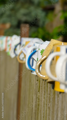 different types and shapes of cups and mugs hanged upside down on the fence © Padisczek
