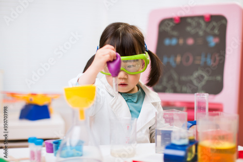 toddler girl pretend play scientist role at home against white background